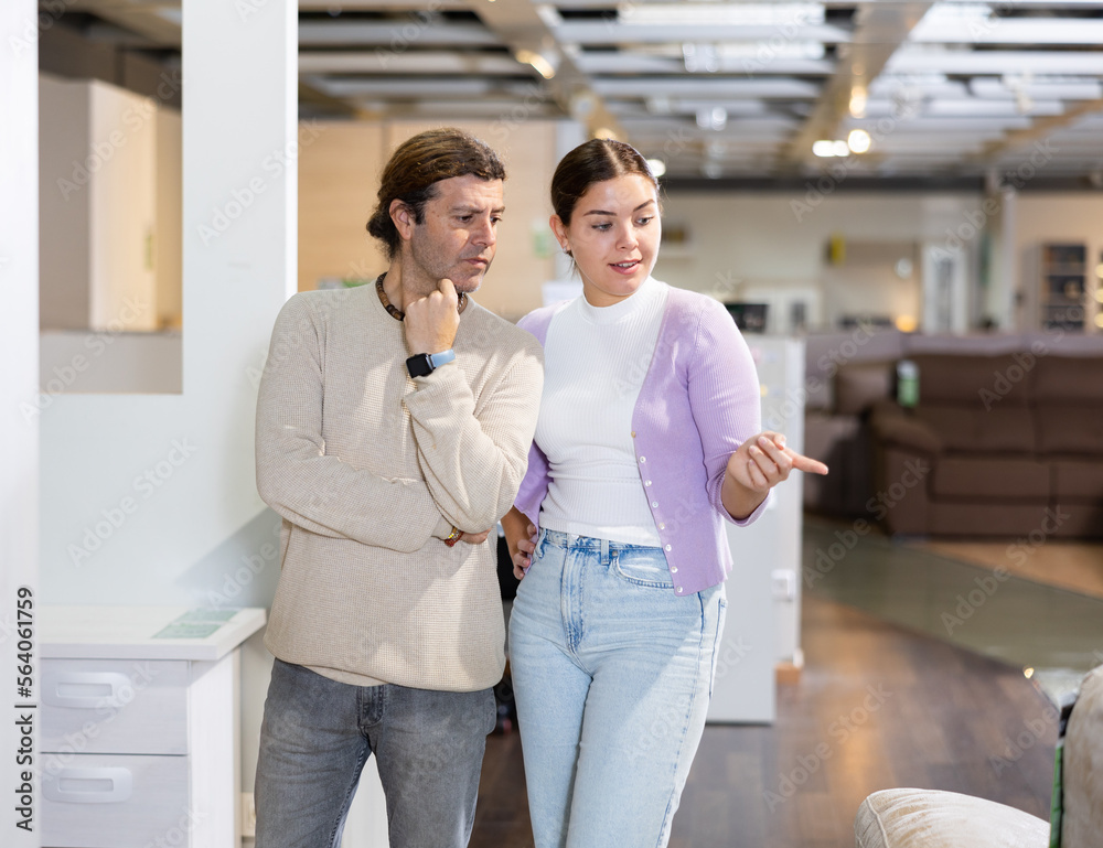 Fototapeta premium guy and girl are testing which of sofas is more comfortable in furniture center
