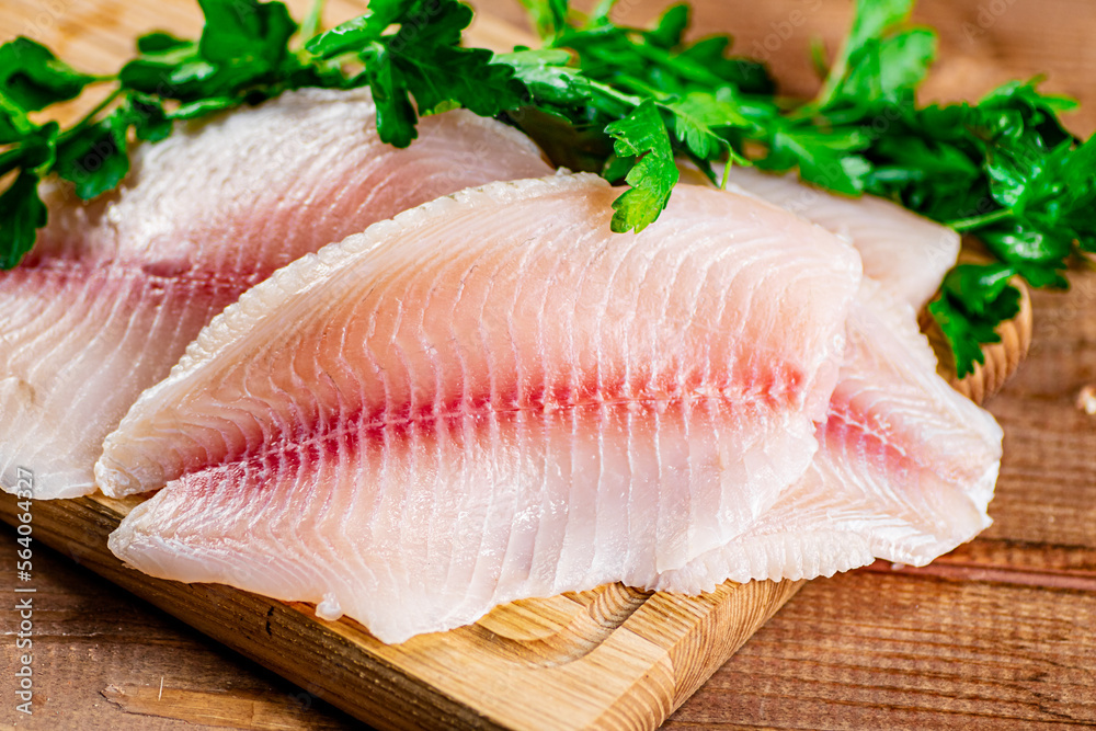 Raw fish fillet with parsley on a cutting board. Raw fish fillet with parsley on a cutting board.