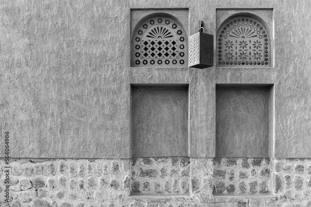 Arabic style window portals in stone wall with ornaments, traditional arabic architecture, Al Fahidi, Dubai, United Arab Emirates, copy space., black and white.