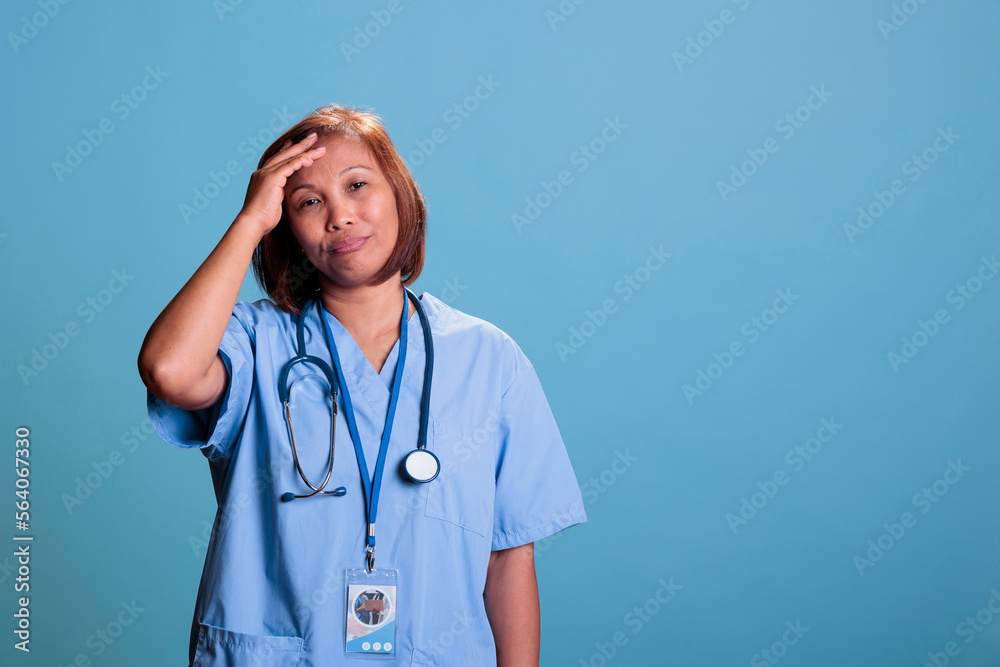 Elderly tired medical assistant suffering from headache after working at health care system expertise. Old depressed physician nurse having migraine during checkup visit appointment Elderly tired medical assistant suffering from headache after working at health care system expertise. Old depressed physician nurse having migraine during checkup visit appointment