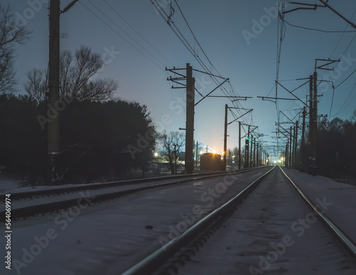 Railroad tracks on a winter night, railroad tracks and city lights in the background, railroad tracks in winter