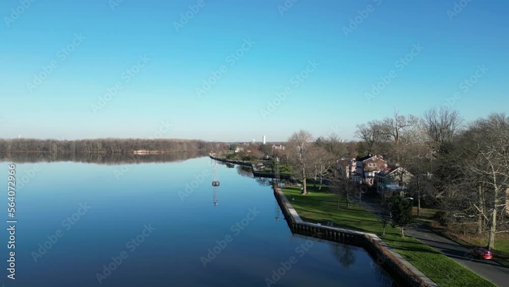 Advancing view over a beautiful park with a river walk sidewalk by a still reflective river Advancing view over a beautiful park with a river walk sidewalk by a still reflective river