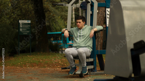 young man exercising in the park athlete exercising on machine  © Julian Digital