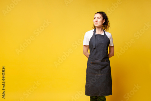 Fotografie girl waiter in uniform stands with her hands behind her back and looks away, bar