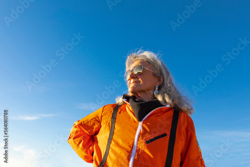 senior woman wearing orange flight suit at sunset photo