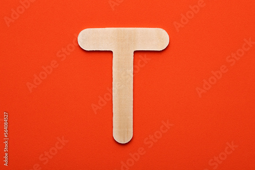 Alphabet letter T - White wood piece on orange foamy background