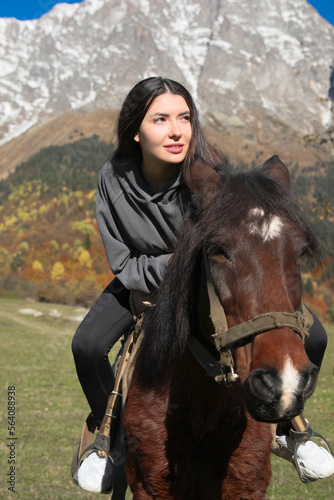 Young woman riding horse in mountains on sunny day. Beautiful pet © New Africa