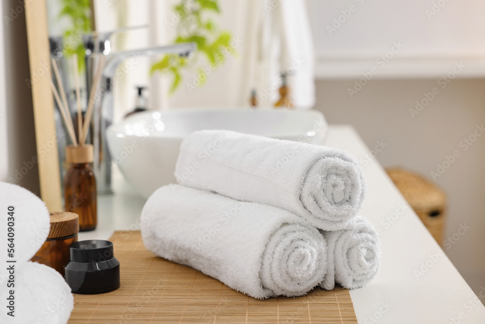 Rolled soft towels on white table in bathroom Rolled soft towels on white table in bathroom