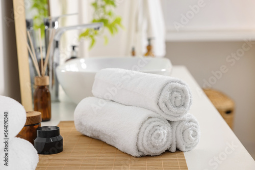 Rolled soft towels on white table in bathroom