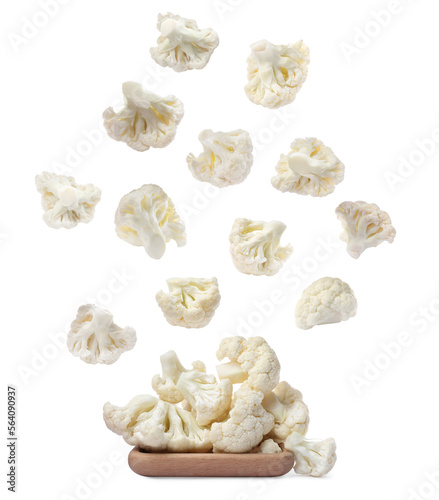Many fresh cauliflower florets falling onto wooden plate on white background