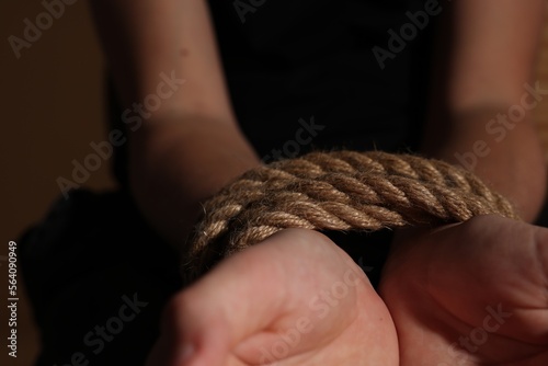 Little boy with tied arms taken hostage on dark background, closeup
