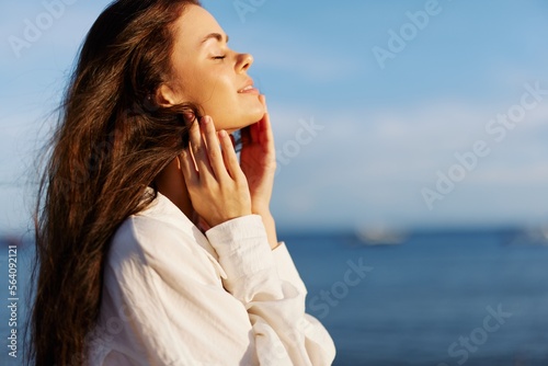 Woman beauty smile with teeth freedom on vacation walking on the beach by the ocean in Bali sunset, happy travel and vacation, sunset light, flying hair, skin and hair care concept in the sun