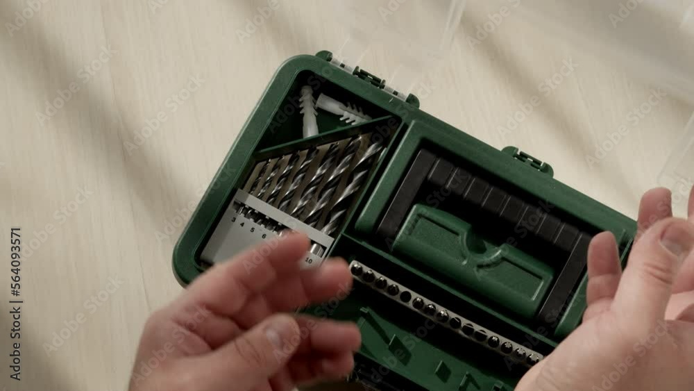 male worker open working green suitcase with tools. carpenter opens transparent compartment with drills for wood and metal to work. concept of production or minor repairs at home. male worker open working green suitcase with tools. carpenter opens transparent compartment with drills for wood and metal to work. concept of production or minor repairs at home.