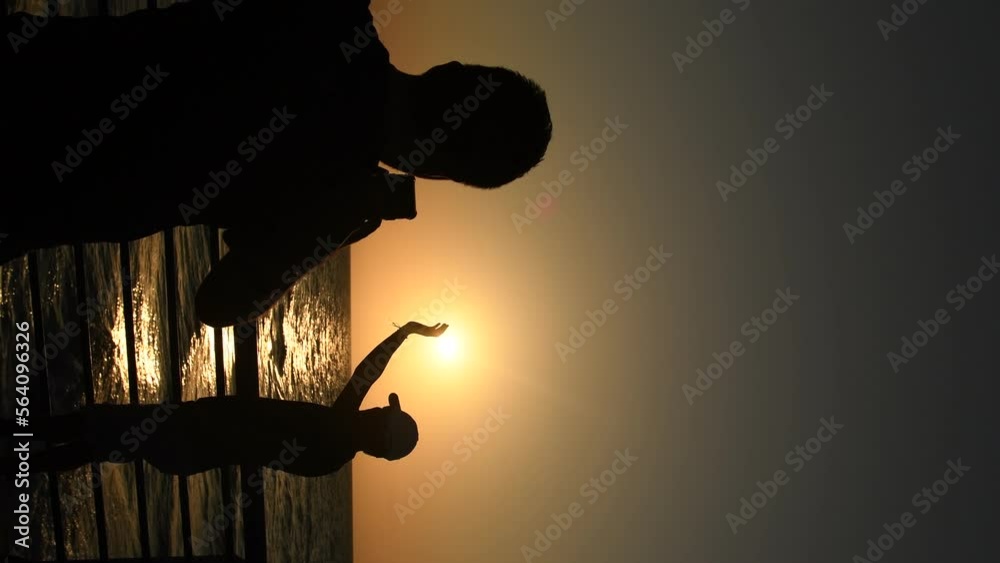 dos personas tomando foto en un atardecer en playas colombianas de tolú vide vertical