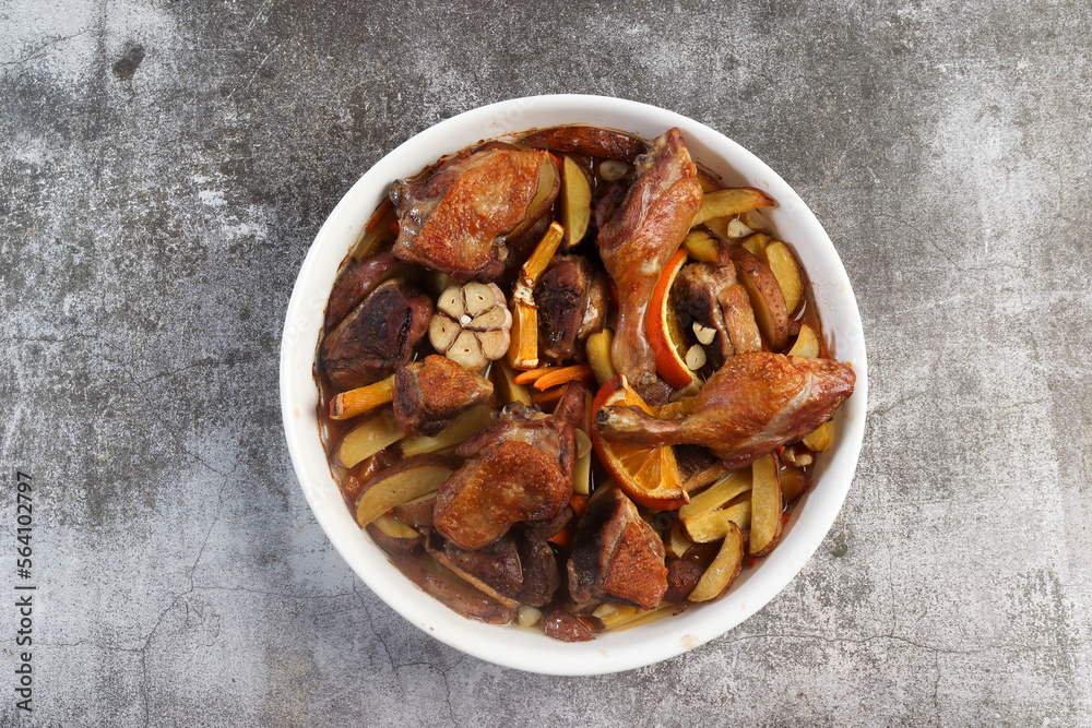 Oven baked Duck with potatoes and carrots in a white baking dish on a dark grey background. Top view, flat lay Oven baked Duck with potatoes and carrots in a white baking dish on a dark grey background. Top view, flat lay