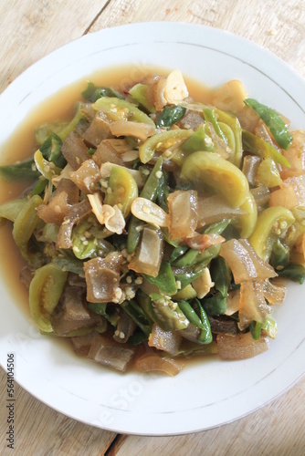 Indonesian cuisine called stir fried green chili kikil in white plate on wooden table photo