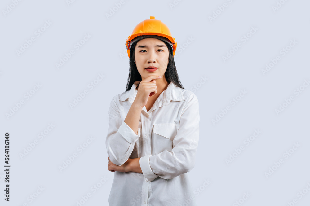 Young female engineer in helmet stand with thoughtful posture Young female engineer in helmet stand with thoughtful posture
