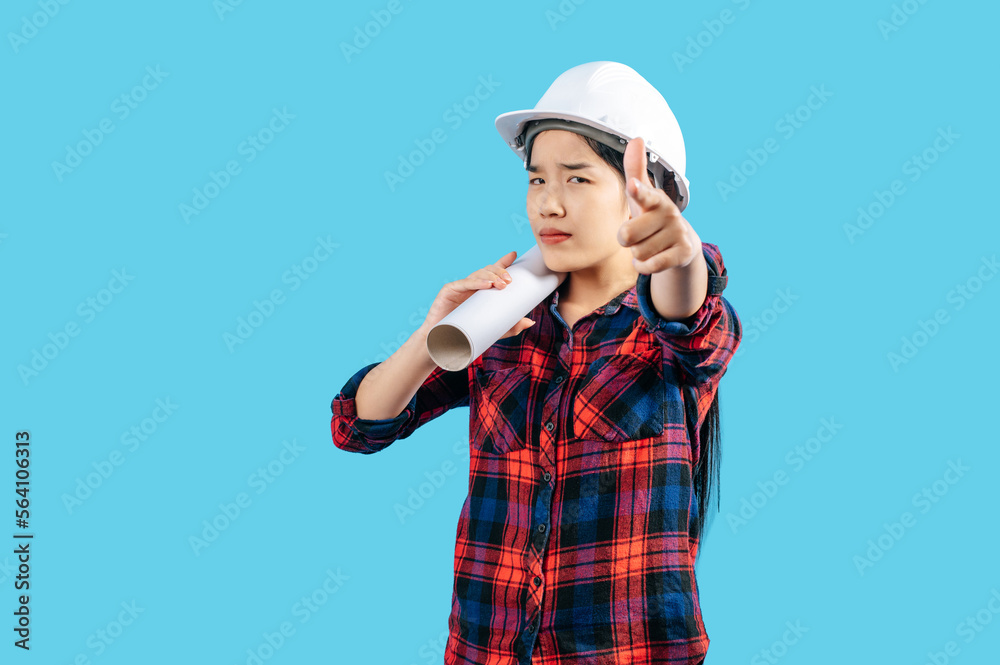 Young female engineer wearing white safety helmet with Blueprints