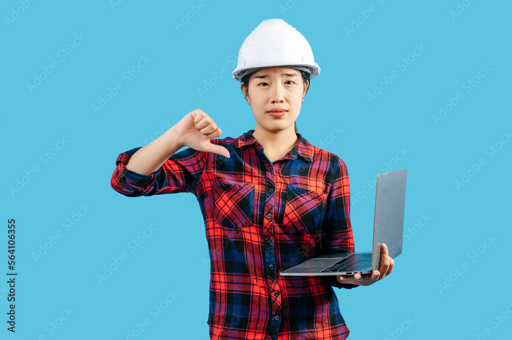 Young female engineer wearing helmet and use laptop computer Young female engineer wearing helmet and use laptop computer