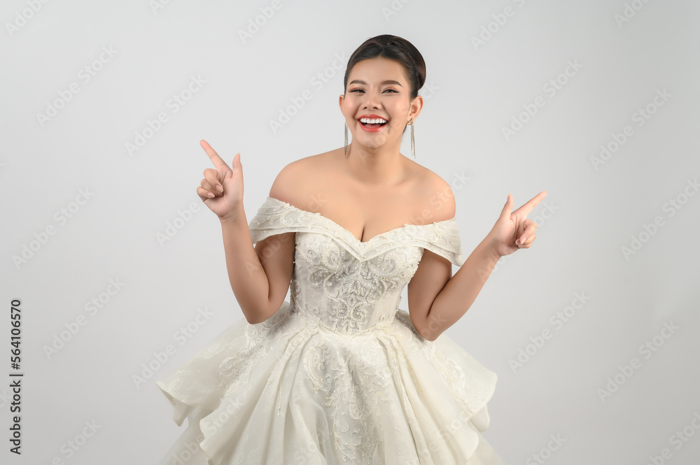 Young asian beautiful bride pose point finger with two hands on white background Young asian beautiful bride pose point finger with two hands on white background