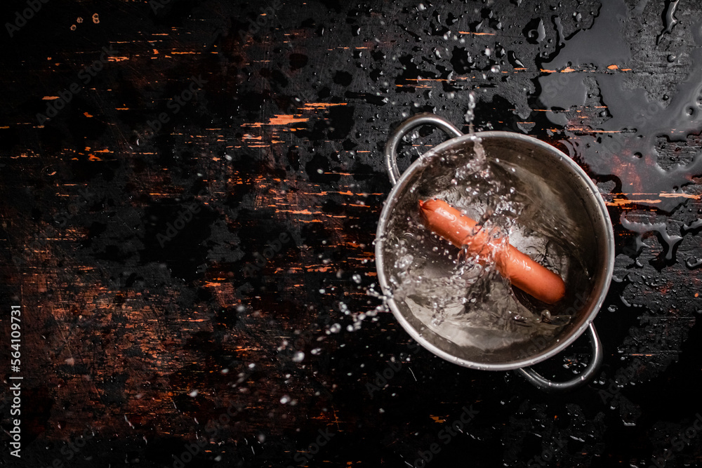 The sausages boiled fall into a pot with splashes of water. The sausages boiled fall into a pot with splashes of water.