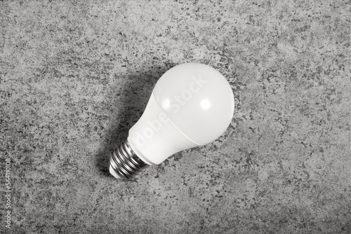 Simple standart form LED energy-saving lamp with E27 screw cap base on gray background. photo