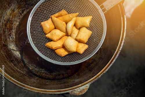 Traditional Kazakh and central asian fresh baursaks are taken out of a large cauldron with a colander. photo