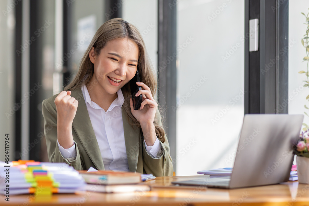 Everyday winner Excited Asian woman raising her arms while sitting at the desk in office, Happy excited employees work or business successful concept. Everyday winner Excited Asian woman raising her arms while sitting at the desk in office, Happy excited employees work or business successful concept.