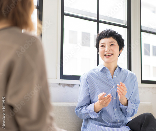 自宅のリビンングで友達と談笑するマチュア世代日本人女性
