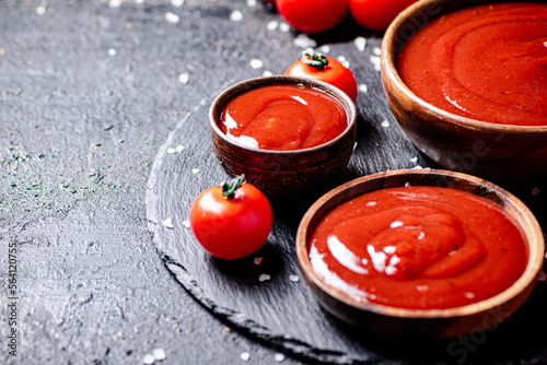 Tomato sauce in a wooden plate on a stone board with salt. 