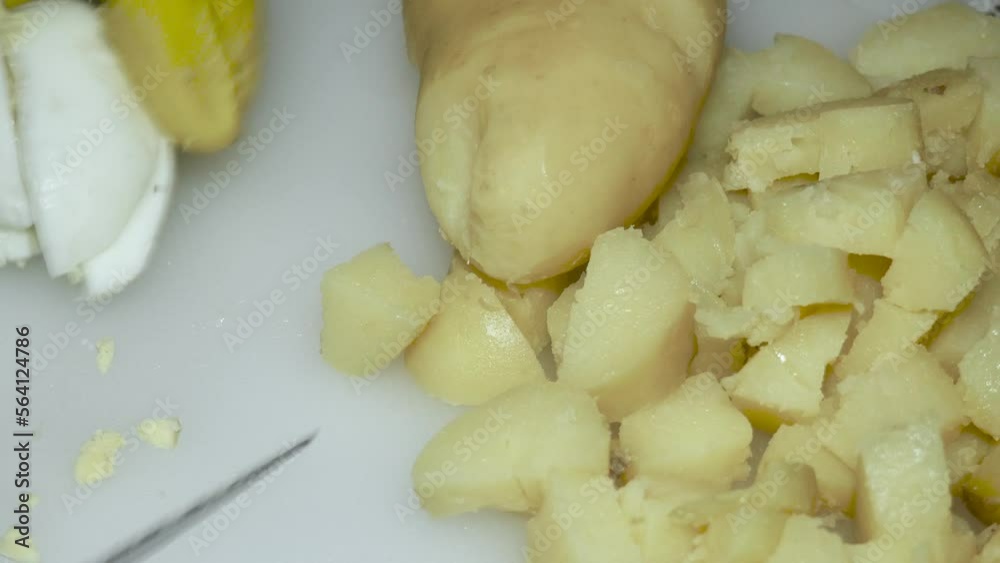 the hand of the cook cuts the boiled egg next to the boiled potatoes the hand of the cook cuts the boiled egg next to the boiled potatoes