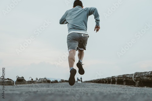 healthy lifestyle young fitness man running at seaside old bridge. Outdoor workout, Healthy lifestyle concept.