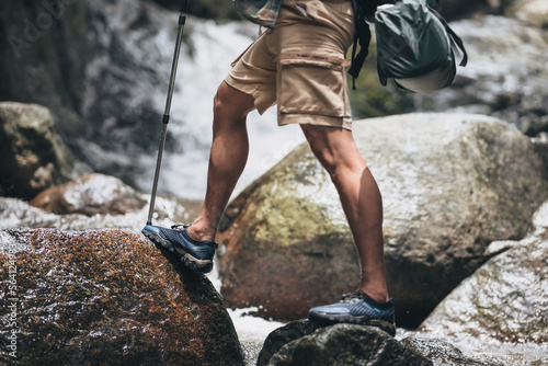 Hikers use trekking pole with backpacks walking through the rock and water on stream in the forest. hiking and adventure concept.