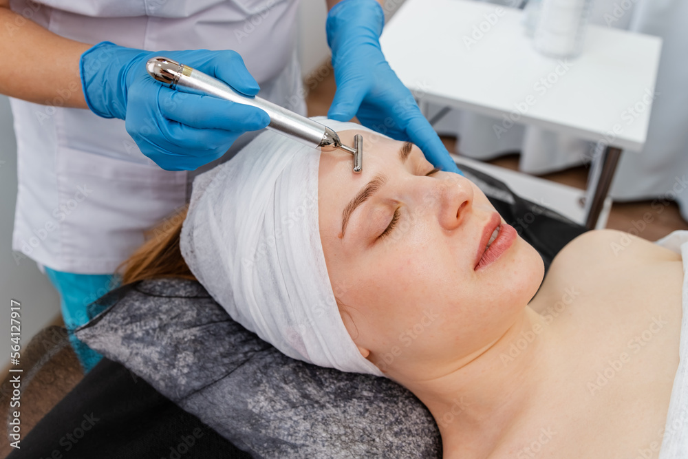Special electric equipment for skincare. Woman in spa having a facial treatment. Beautiful woman face receiving facial microcurrent treatment with apparatus from therapist in beauty wellness salon. Special electric equipment for skincare. Woman in spa having a facial treatment. Beautiful woman face receiving facial microcurrent treatment with apparatus from therapist in beauty wellness salon.