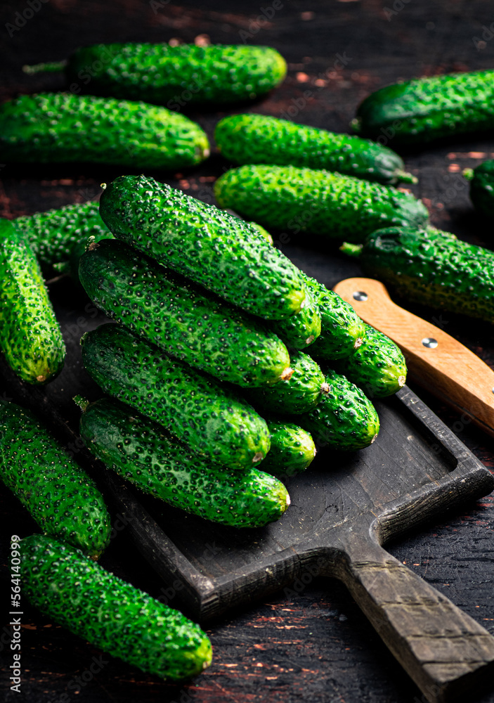Fresh cucumbers on a wooden cutting board. 