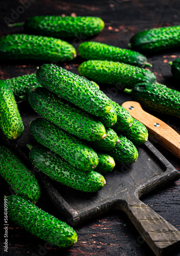 Fresh cucumbers on a wooden cutting board. 