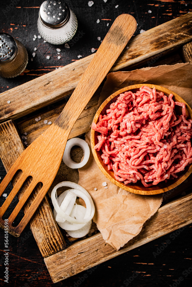 Minced meat on a wooden tray with onion rings. Minced meat on a wooden tray with onion rings.