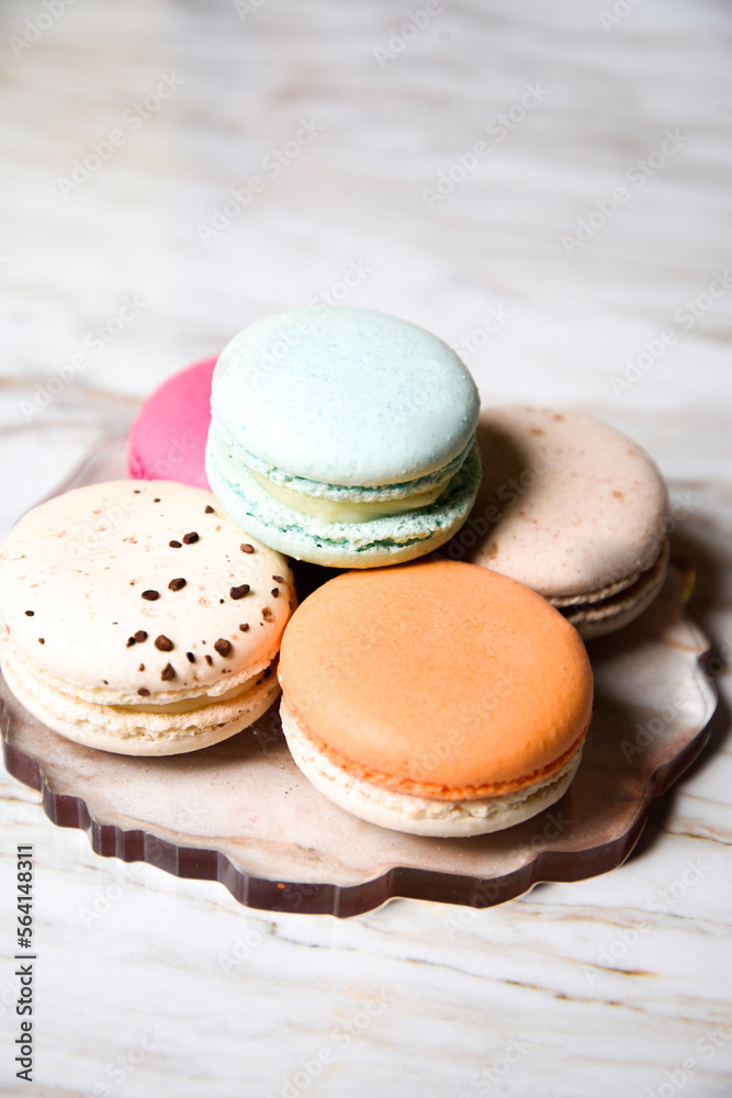 Macaron pink, orange and beige, blue on marble style. A beautiful and beautiful French dessert. Fruits and epoxy resin and flowers on the background