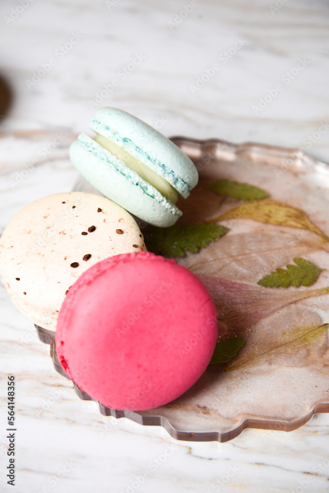 Fototapeta premium Macaron pink, orange and beige, blue on marble style. A beautiful and beautiful French dessert. Fruits and epoxy resin and flowers on the background