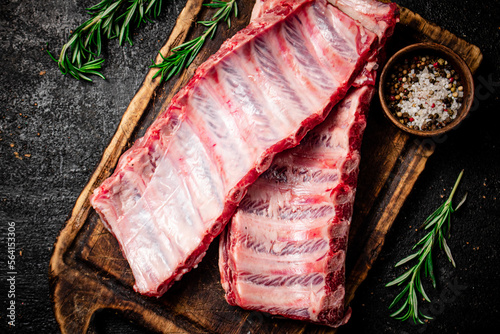 Raw ribs with rosemary and spices on a cutting board. 