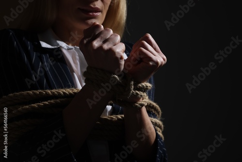 Woman tied up and taken hostage on dark background, closeup. Space for text