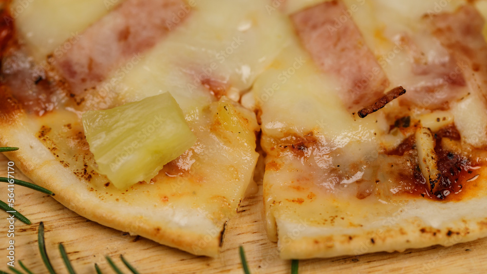 Closeup top view studio shot of round hot oven baked tasty delicious Italian homemade ham pineapple original Hawaiian soft bread crust pizza on wooden plate pan with tomatoes and ketchup on table Closeup top view studio shot of round hot oven baked tasty delicious Italian homemade ham pineapple original Hawaiian soft bread crust pizza on wooden plate pan with tomatoes and ketchup on table