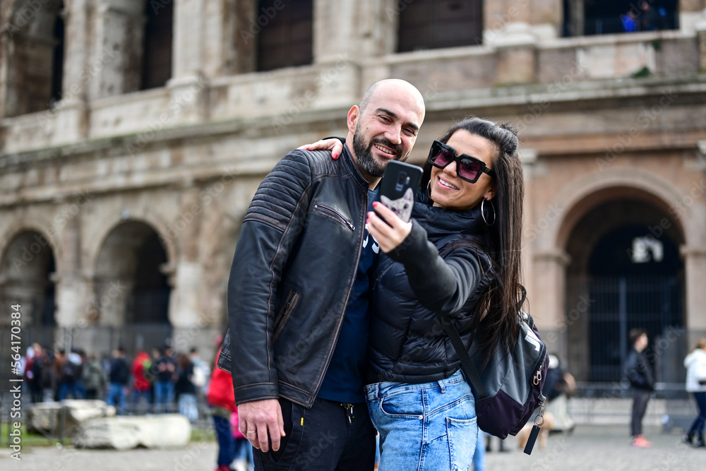 Happy  Beautiful Tourists  couple traveling at Rome, Italy, poses in front of  Colosseum  at, Rome, Italy