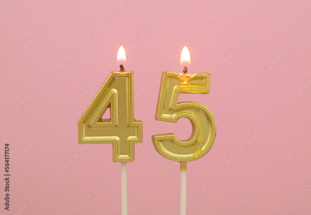 Gold birthday candles burning on pink background, number 45 Gold birthday candles burning on pink background, number 45