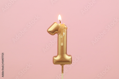 Burning birthday candles on pink background, number 1