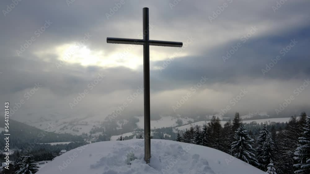 A Christian cross in a winter mountain landscape. Layers of clouds, shining sun rays, timelapse, 