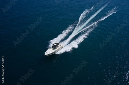 Large motor boat with an awning fast movement on dark water aerial view.