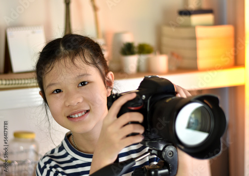 Asian girls having fun and smiling happily learning digital camera photography skills in home studio.