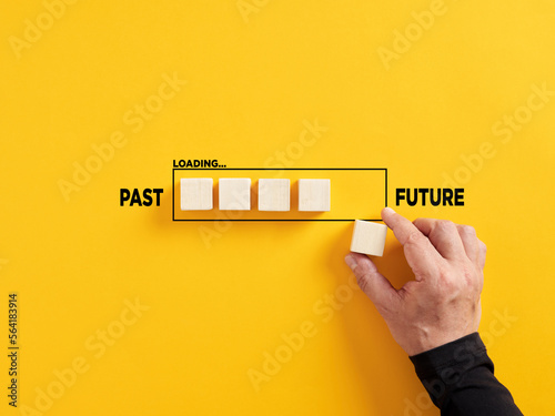 Transition of time from past to future concept. Hand places a wooden cube to the loading bar with the words past and future. photo