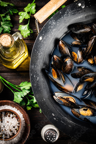 Mussels in a saucepan with parsley and spices. 